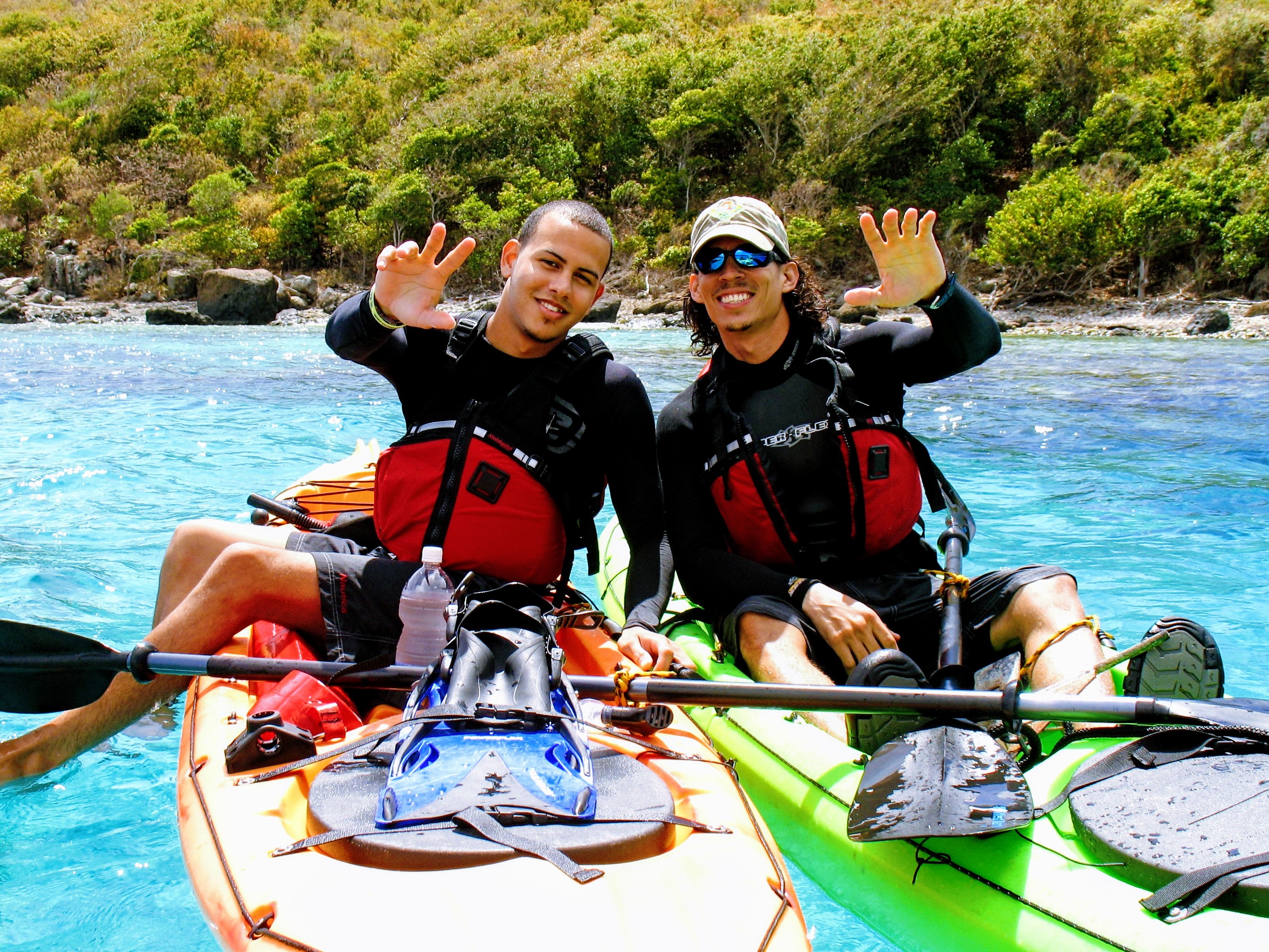Two men smile and wave from their kayaks before a snorkeling in culebra session with the culebra day trip of kayaking puerto rico